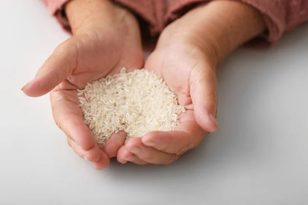 Hands of elderly woman with rice on white background. Concept of poverty