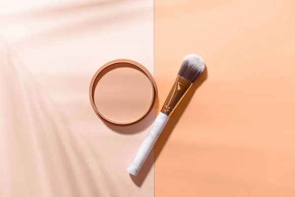 Makeup brush with facial powder on color background