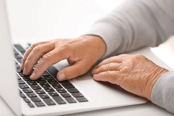 Elderly woman with modern laptop on white table, closeup — Stock Photo, Image
