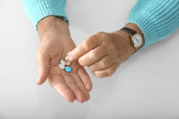 Hands of elderly woman with pills on white background — Stock Photo, Image