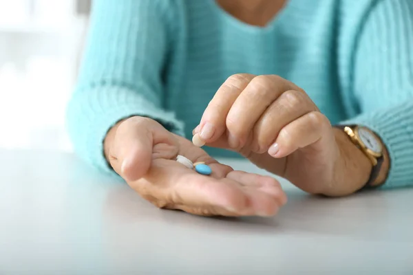 Mujer mayor con pastillas en la mesa blanca, primer plano — Foto de Stock