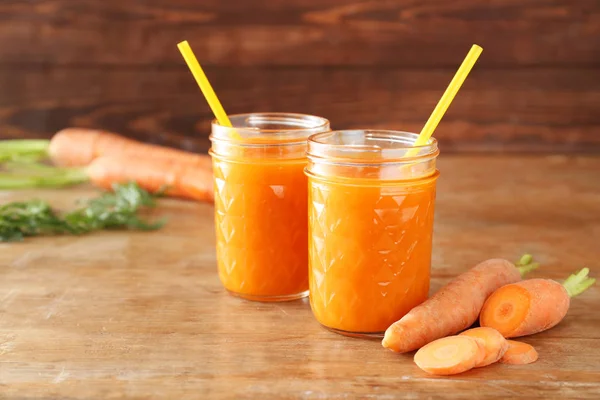 Jars of tasty carrot juice on wooden table — Stock Photo, Image