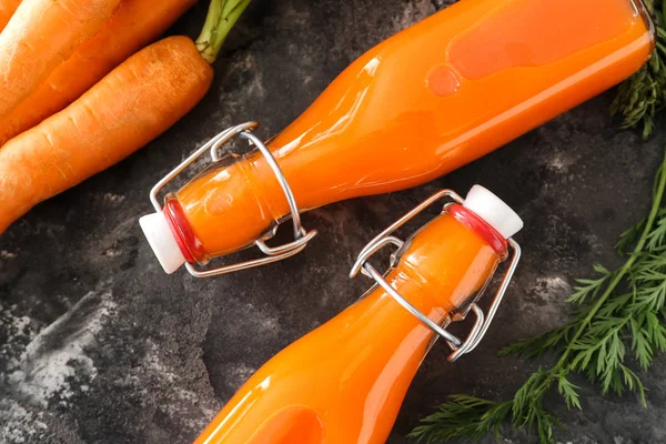 Bottles of tasty carrot juice on grunge background — Stock Photo, Image