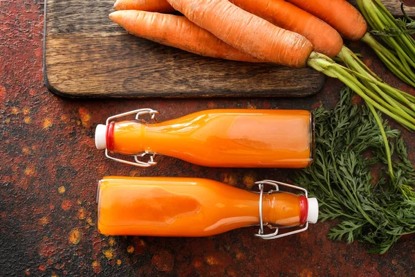 Flaschen leckerer Karottensaft auf farbigem Hintergrund — Stockfoto