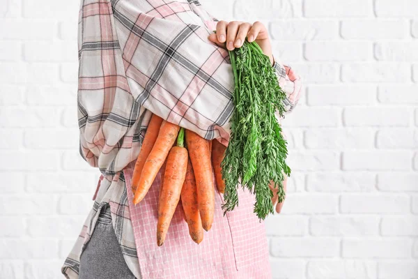 Woman holding fresh carrots on white brick background, closeup — Stock Photo, Image