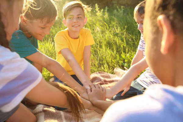 Grupp barn som sätter händer tillsammans utomhus — Stockfoto