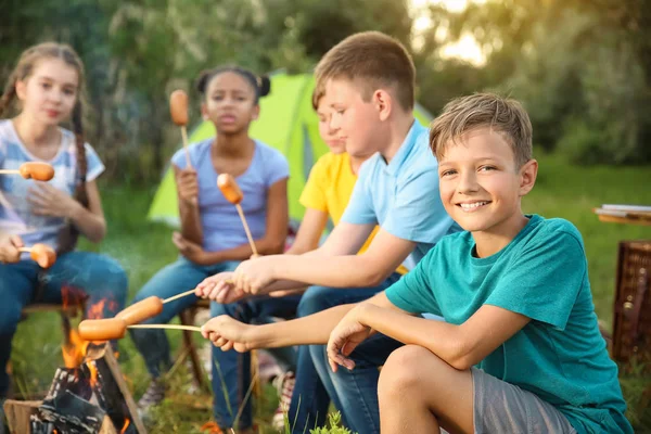 Gruppo di bambini che cucinano salsicce sul falò — Foto Stock