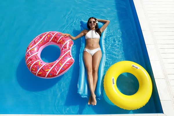 Mulher nova bonita que relaxa no colchão inflável na piscina — Fotografia de Stock