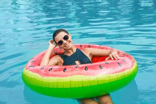 Hermosa mujer joven relajándose en el anillo inflable en la piscina —  Fotos de Stock