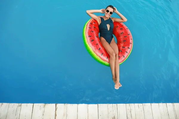Hermosa mujer joven relajándose en el anillo inflable en la piscina —  Fotos de Stock