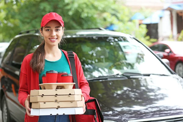 Female worker of food delivery service near car outdoors — Stock Photo, Image