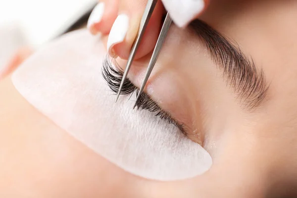 Ung kvinna genomgår ögonfrans förlängning förfarande i skönhetssalong, närbild — Stockfoto