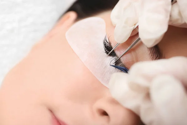 Young woman undergoing eyelash extension procedure in beauty salon, closeup — Stock Photo, Image