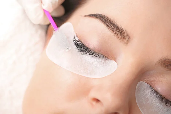 Young woman undergoing eyelash extension procedure in beauty salon, closeup — Stock Photo, Image