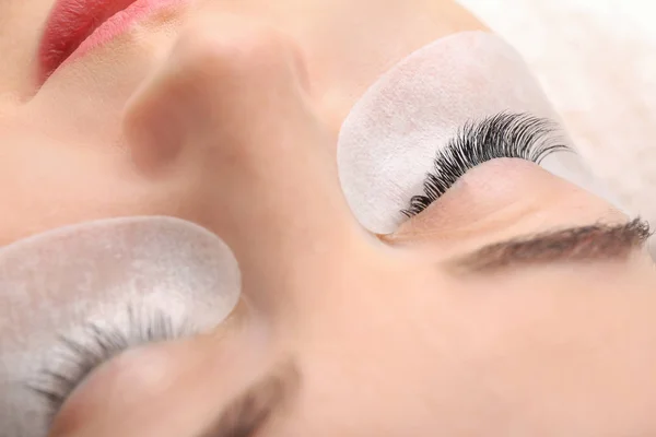 Young woman undergoing eyelash extension procedure in beauty salon, closeup — Stock Photo, Image