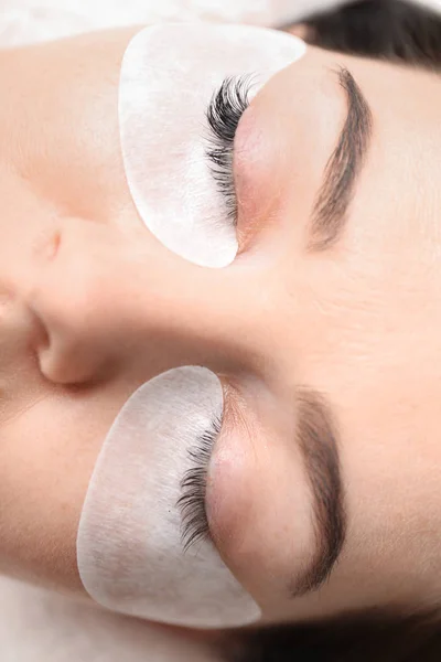 Young woman undergoing eyelash extension procedure in beauty salon, closeup — Stock Photo, Image