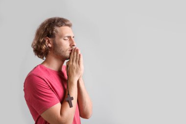 Dinli genç adam ışık arka plan üzerinde dua