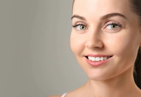 Belle jeune femme avec des extensions de cils sur fond gris — Photo