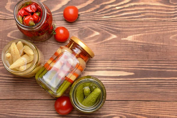 Jars with different canned vegetables on wooden background — Stock Photo, Image