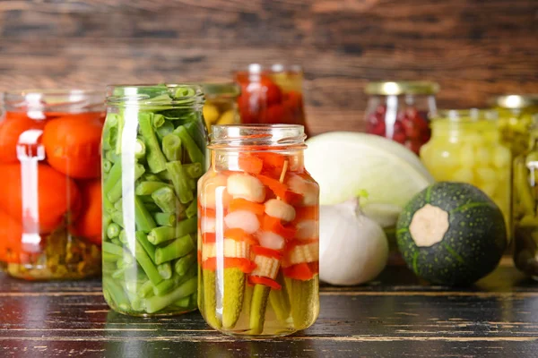 Jars with different canned vegetables on wooden table — Stock Photo, Image