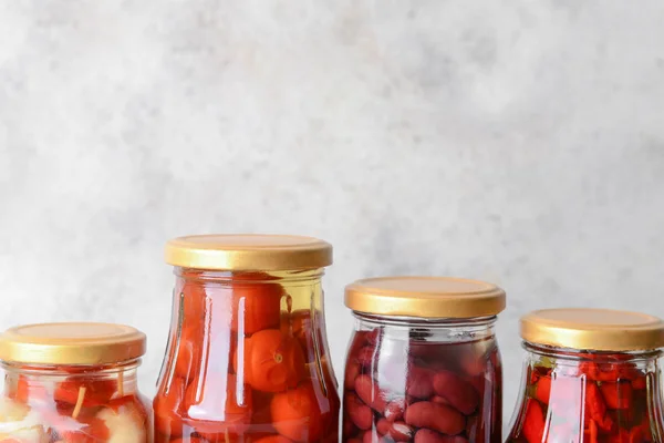 Jars with different canned vegetables and beans on grey background — Stock Photo, Image