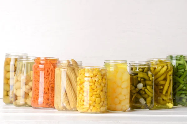 Jars with different canned vegetables on white table — Stock Photo, Image