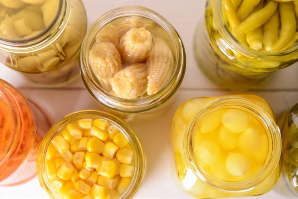 Jars with different canned vegetables on white table — Stock Photo, Image