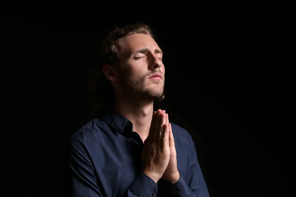 Religious young man praying on dark background — Stock Photo, Image