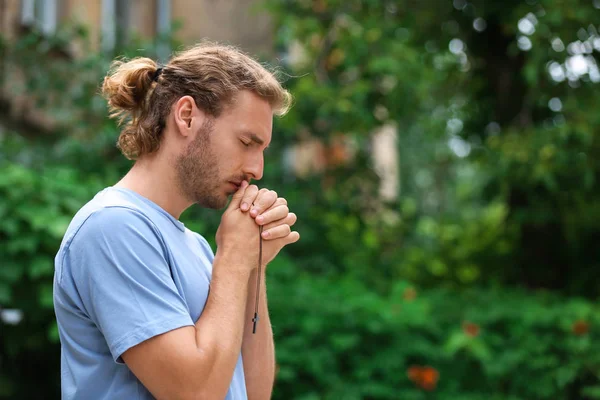 Religious young man praying outdoors — Stock Photo, Image