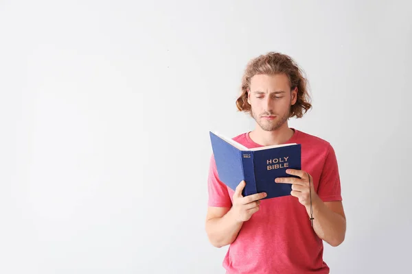 Religiöser junger Mann liest Bibel auf weißem Hintergrund — Stockfoto