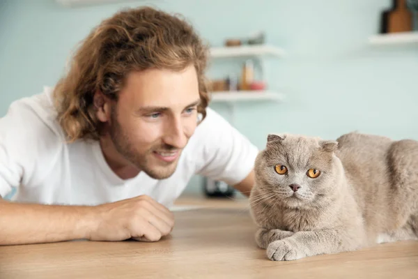 Man with cute funny cat at kitchen table — Stock Photo, Image