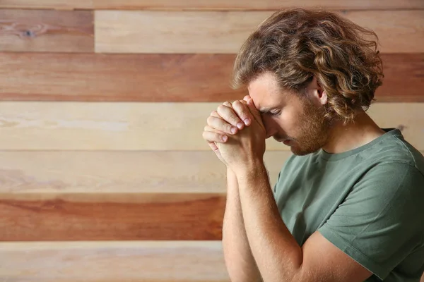 Religious young man praying on wooden background — Stock Photo, Image