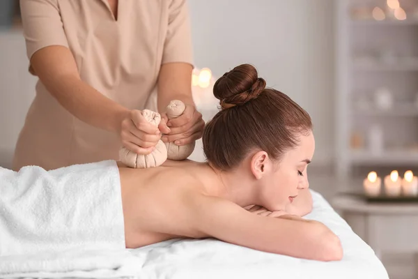 Junge Frau bei Massage mit Kräutertüten im Wellness-Salon — Stockfoto