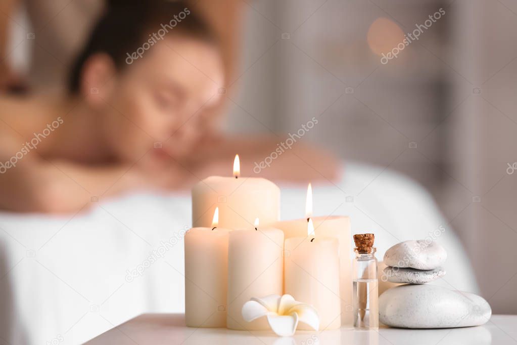 Beautiful burning candles with stones and essential oil on table in spa salon