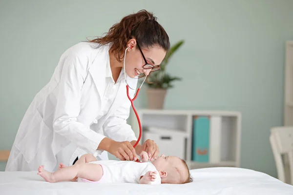 Лікар-педіатр, який вивчає маленьку дитину в клініці — стокове фото