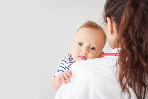 Pediatrician with little baby on light background — Stock Photo, Image