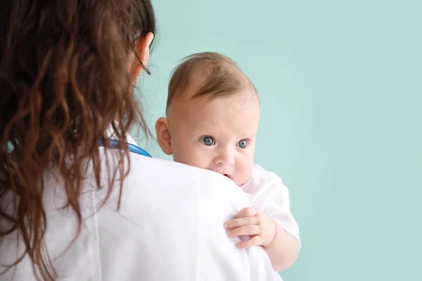 Kinderarzt mit niedlichem Baby auf farbigem Hintergrund — Stockfoto