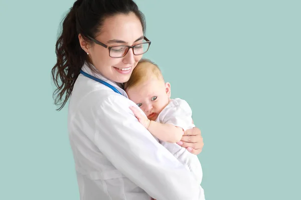 Pediatra con lindo bebé en el fondo de color — Foto de Stock