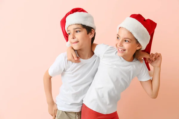 Glückliche kleine Kinder in Weihnachtsmützen auf farbigem Hintergrund — Stockfoto