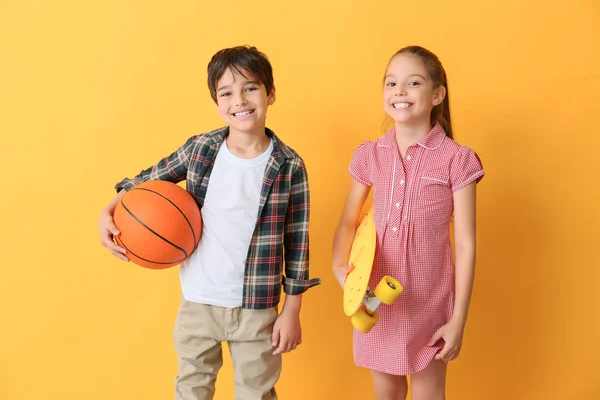 Carino bambini piccoli con palla e skateboard su sfondo di colore — Foto Stock