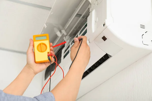 Electrician repairing air conditioner indoors — Stock Photo, Image