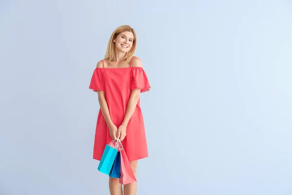 Mulher bonita feliz com sacos de compras no fundo de cor — Fotografia de Stock