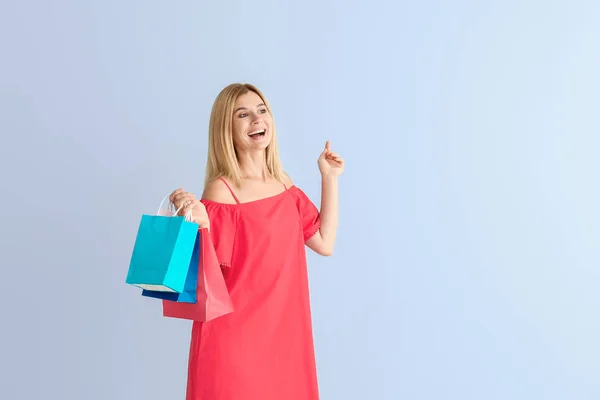 Glücklich schöne Frau mit Einkaufstaschen auf farbigem Hintergrund — Stockfoto