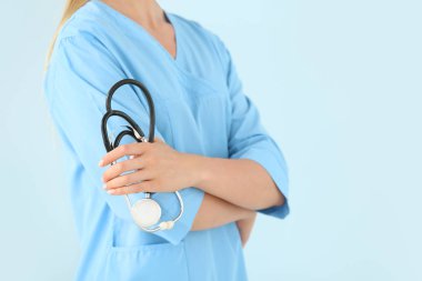 Renk arka planda stetoskoplu kadın hemşire, closeup