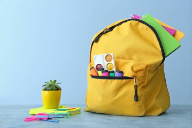 Okul çantası ve kırtasiye masadaki renk arkaplanına karşı