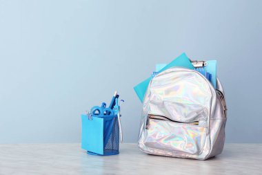 Okul çantası ve kırtasiye masadaki renk arkaplanına karşı