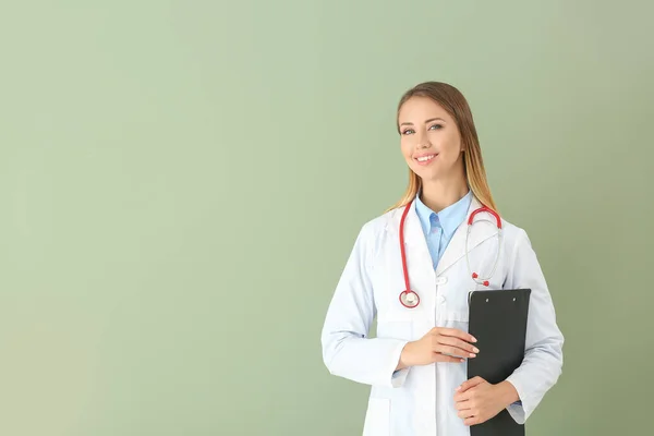Female doctor with stethoscope and clipboard on color background — Stock Photo, Image