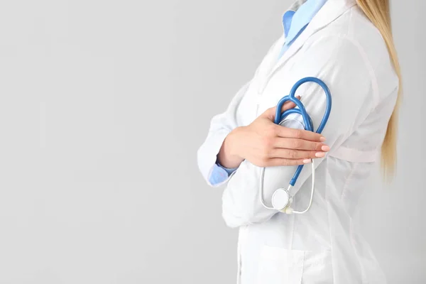 Female doctor with stethoscope on light background — Stock Photo, Image