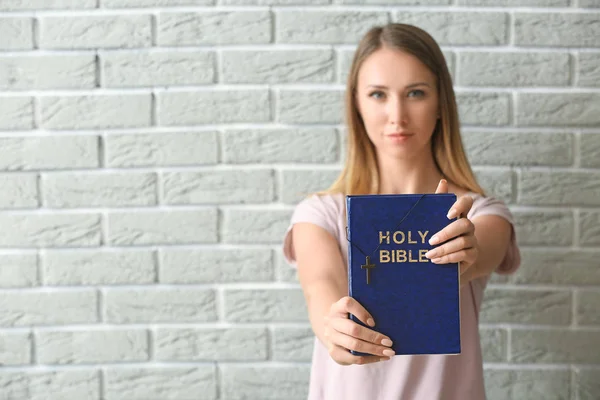 Religijna młoda kobieta z Biblii przeciwko ścianie cegły — Zdjęcie stockowe