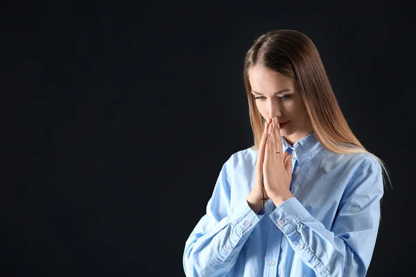 Religious young woman praying on dark background — Stock Photo, Image